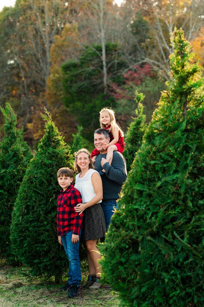 Family of four with a daughter on dad’s shoulders at a Christmas tree farm mini session in Portland, TN