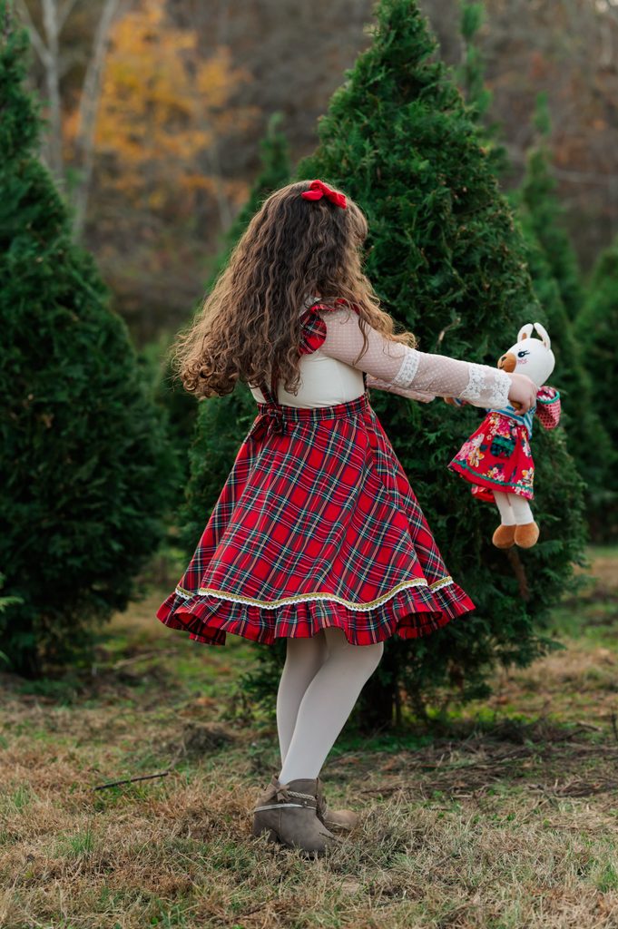 Girl twirling with her stuffed llama at a Christmas tree farm mini session at Big Sky Farm, Portland TN